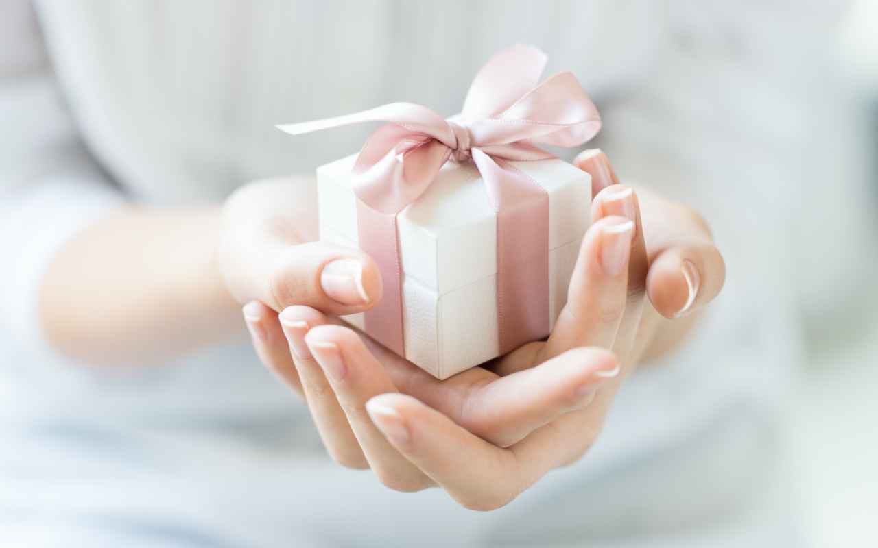 Small gift box in pink ribbon held in the hands of a woman