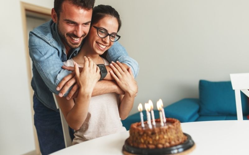 Couple embrace celebrating a birthday with cake and candles