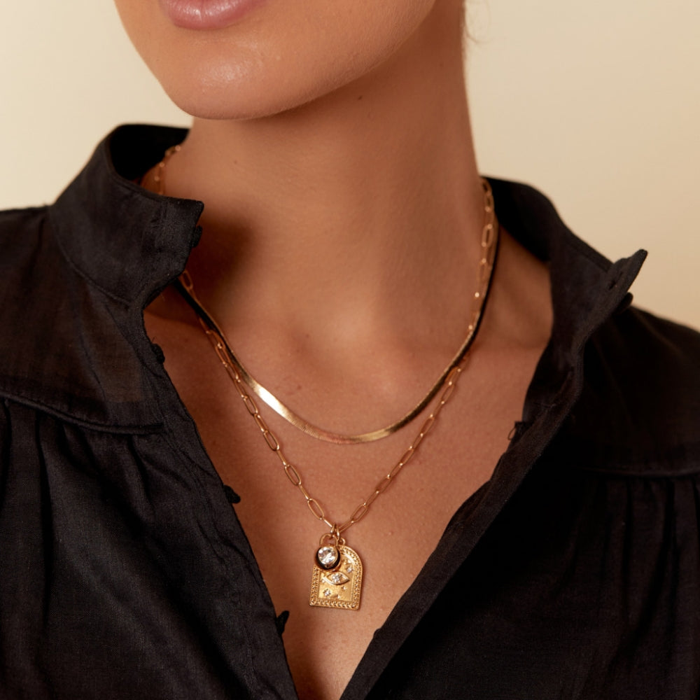 Double layered gold snake chain and charm necklace on model with diamante detailing