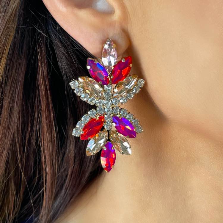 Close up of Glam diamante statement earrings Multi coloured in rose/mauve on ear