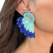 angel wing rice bead, sequin and diamante stud earrings in aqua and blue on model